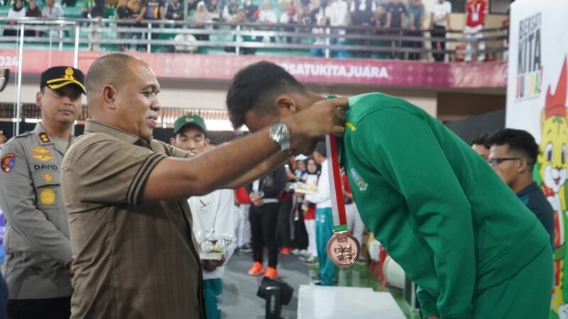 Pj BUpati Langkat Faisal Hasrimy menyerahkan mendali kepada sang juara di Cabor Sambo.(red)