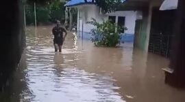 Seorang wanita tengah melintasi jalan yang terendam banjir di Kota Binjai