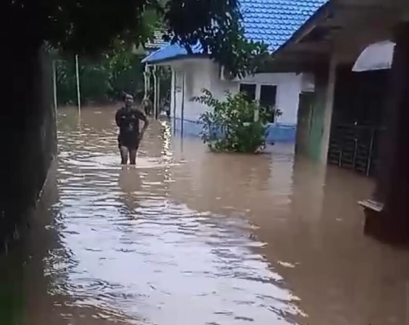 Seorang wanita tengah melintasi jalan yang terendam banjir di Kota Binjai