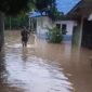 Seorang wanita tengah melintasi jalan yang terendam banjir di Kota Binjai