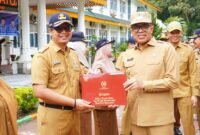 Pj Bupati Langkat Faisal Hasrimy saat memberikan penghargaan kepada salahsatu ASN di Langkat